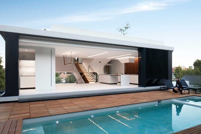 exterior upper level of modern home with sliding doors open to a pool