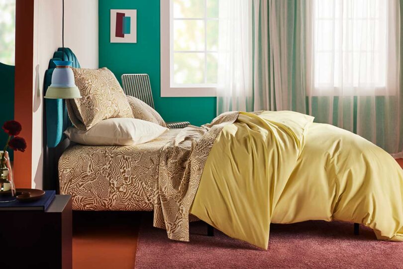 side view of modern bedroom with green upholstered headboard and colorful bedding