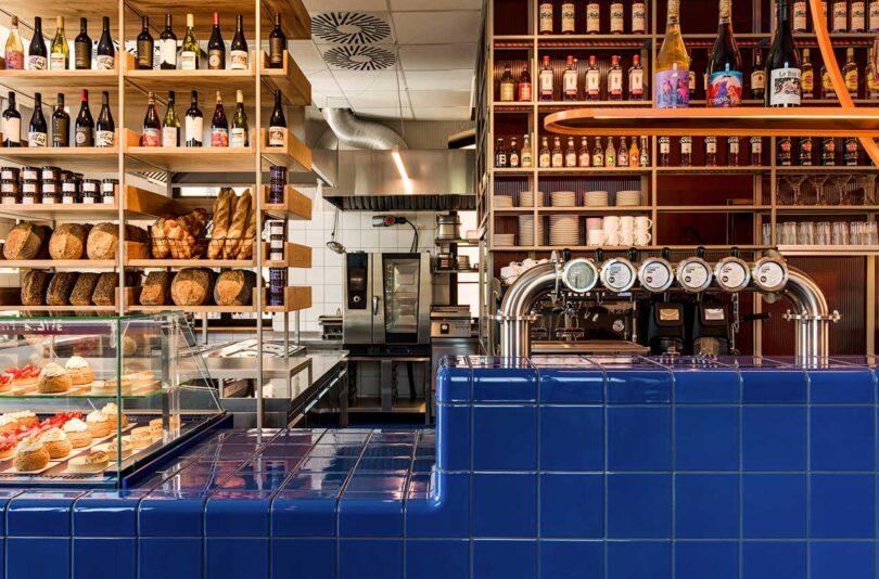 commercial restaurant interior with modern aesthetic featuring blue tiled counter and pastries stacked on shelving