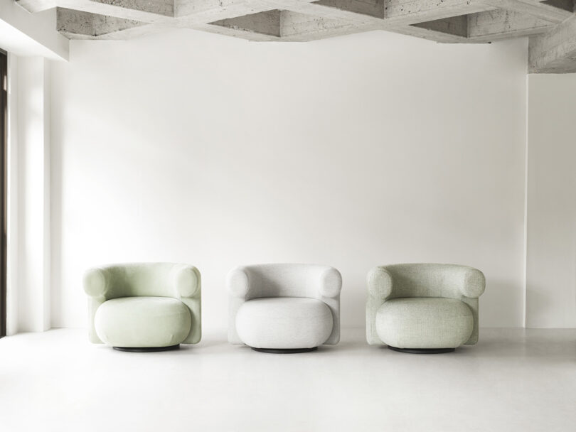 three modern white armchairs in a studio space
