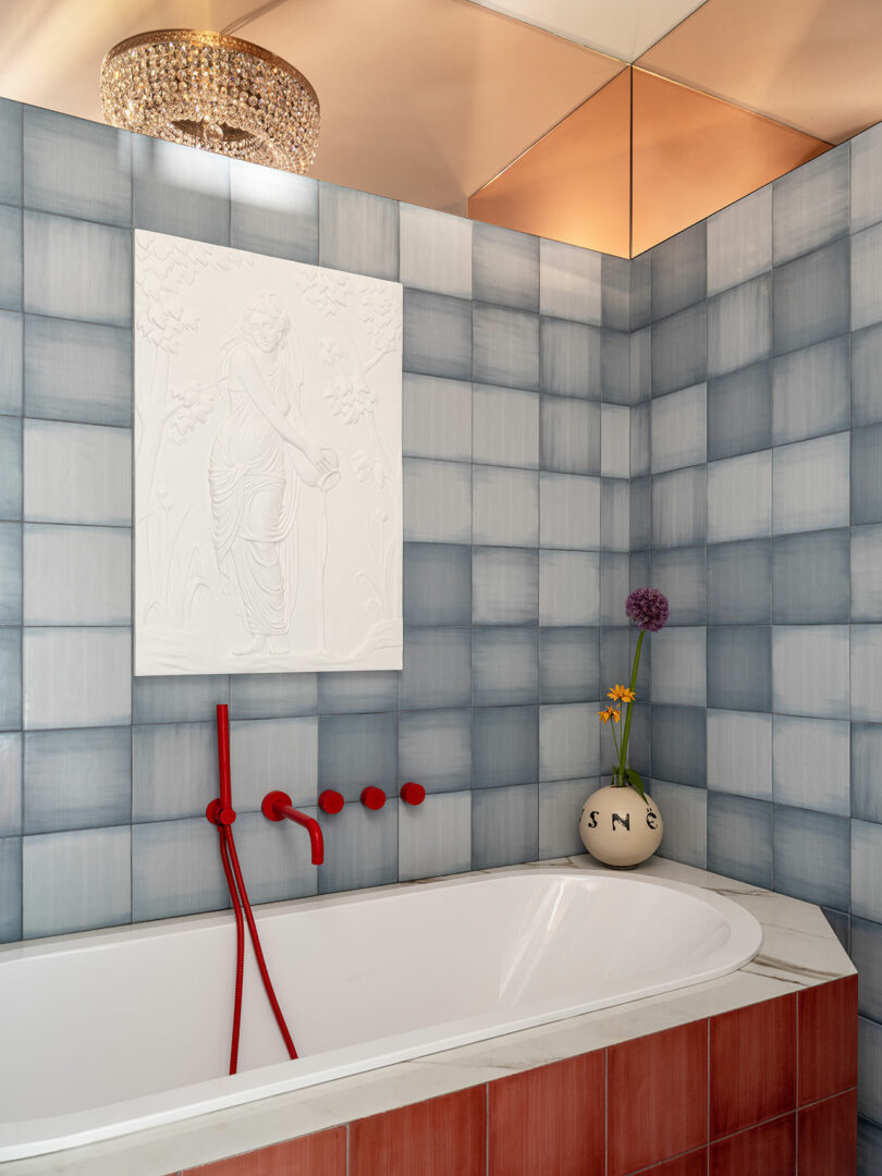 angled view of modern bathtub niche with red bathtub and gray/blue wall tiles