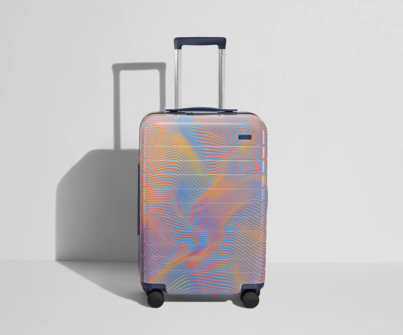 Multicolored AWAY x Resident Advisor Soundwave hardshell luggage with wheels and an extended handle against a white background with shadow.