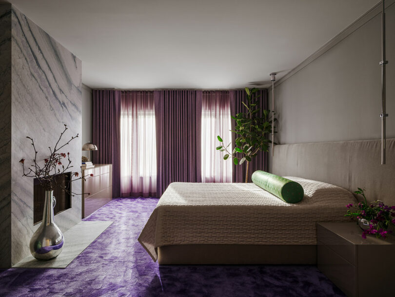 A modern bedroom with a textured bedspread, purple accents, and natural light filtering through sheer curtains.