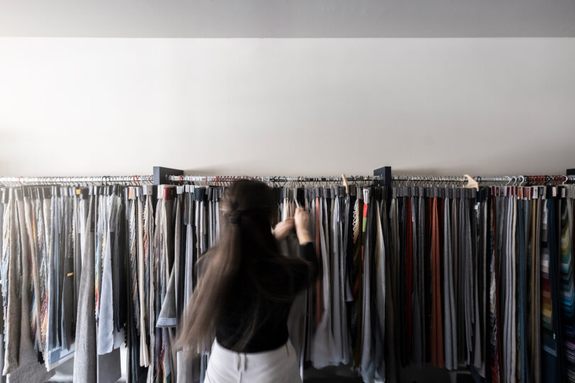 Woman browsing through NOA clothing on racks in a store.