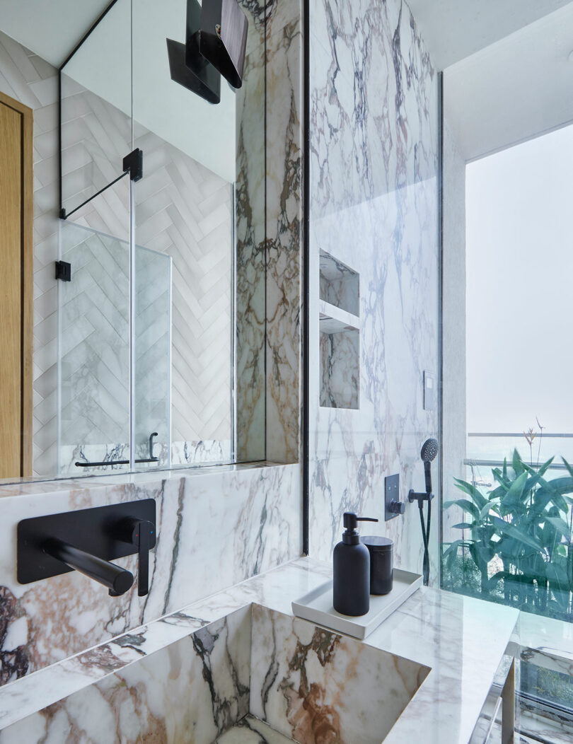 Modern bathroom design with marble finishes and herringbone tile pattern.