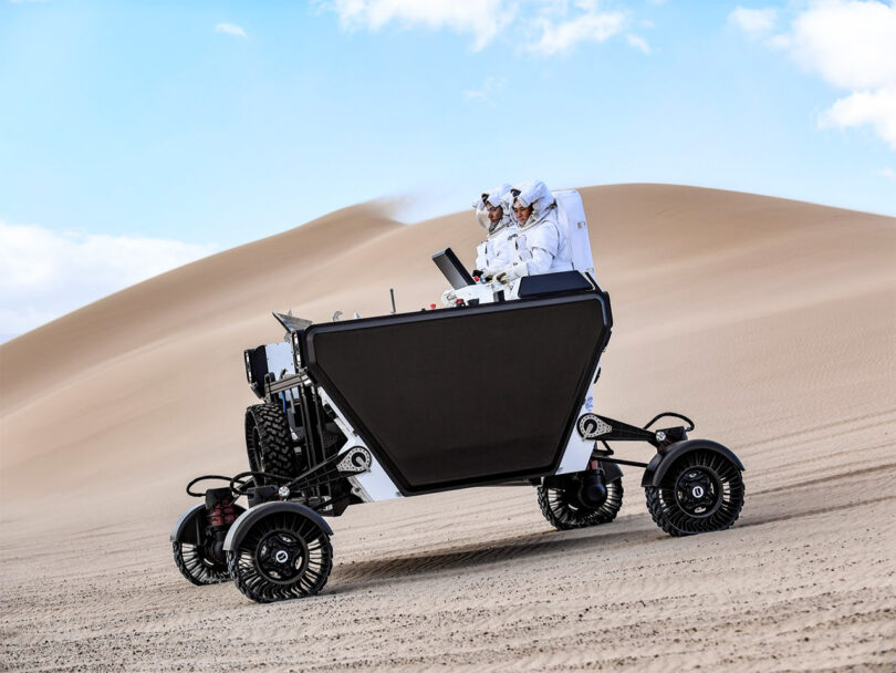 Two astronauts in spacesuits operating the Artemis 5 Lunar Terrain Vehicle concept in Death Valley desert, a location chosen for its resemblance to the lunar landscape.