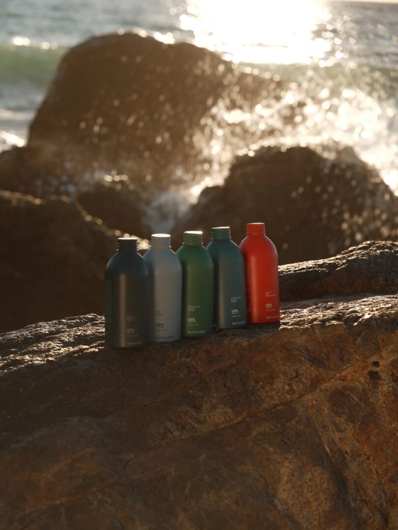 Uni. refillable body care system displayed on a rock at the beach